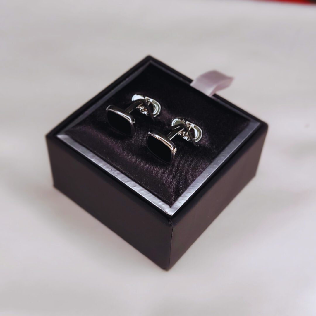 A pair of cufflinks in a box on top of a table.