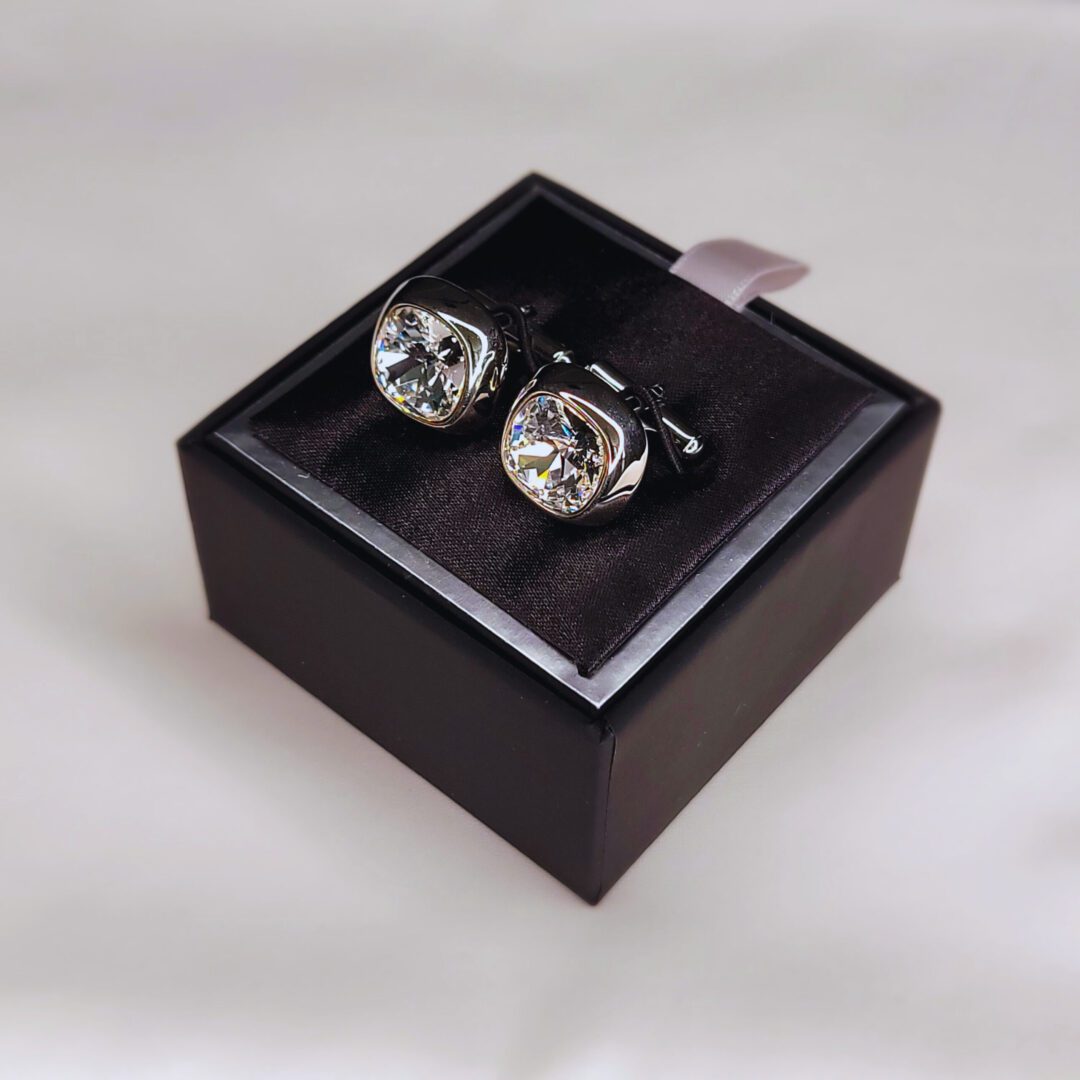 A pair of cufflinks in a box on top of a table.