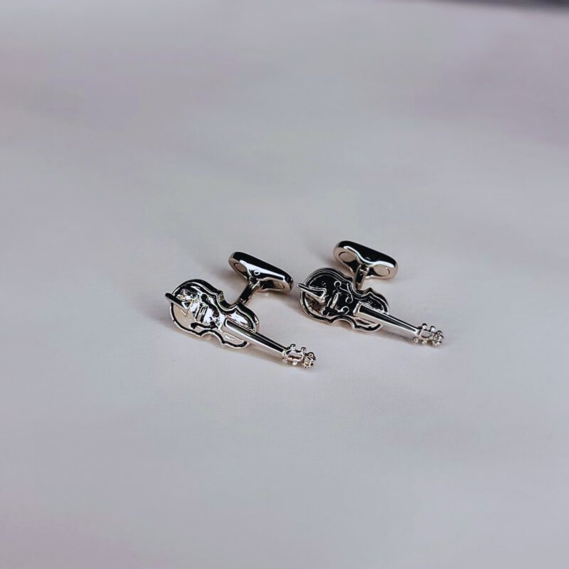 A pair of silver cufflinks with a guitar on them.