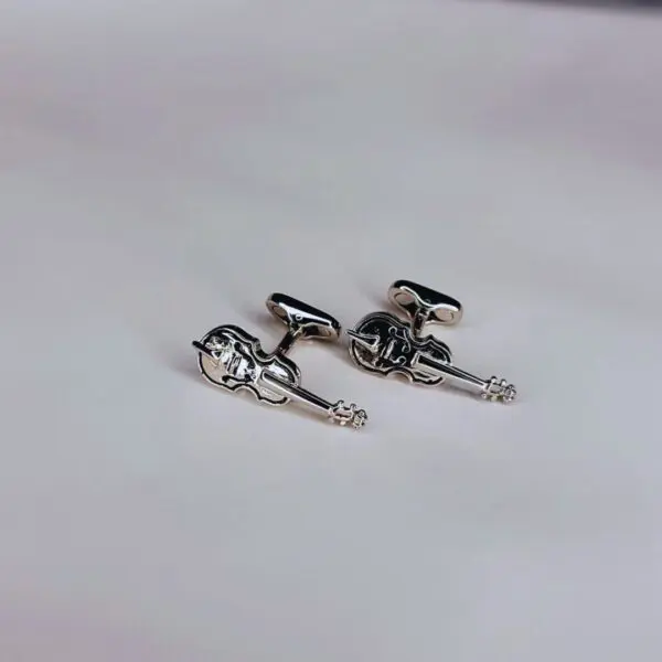 A pair of silver cufflinks with a man 's head and hands.