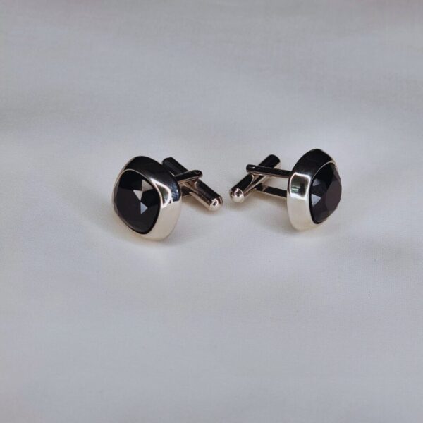 A pair of cufflinks with black stones on top.