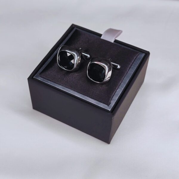 A pair of cufflinks in a box on top of a table.