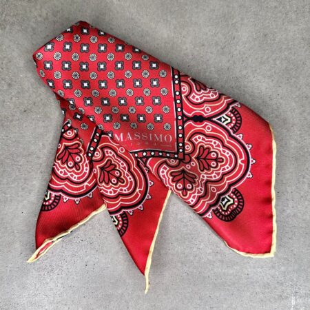 A red and black patterned scarf laying on the ground.