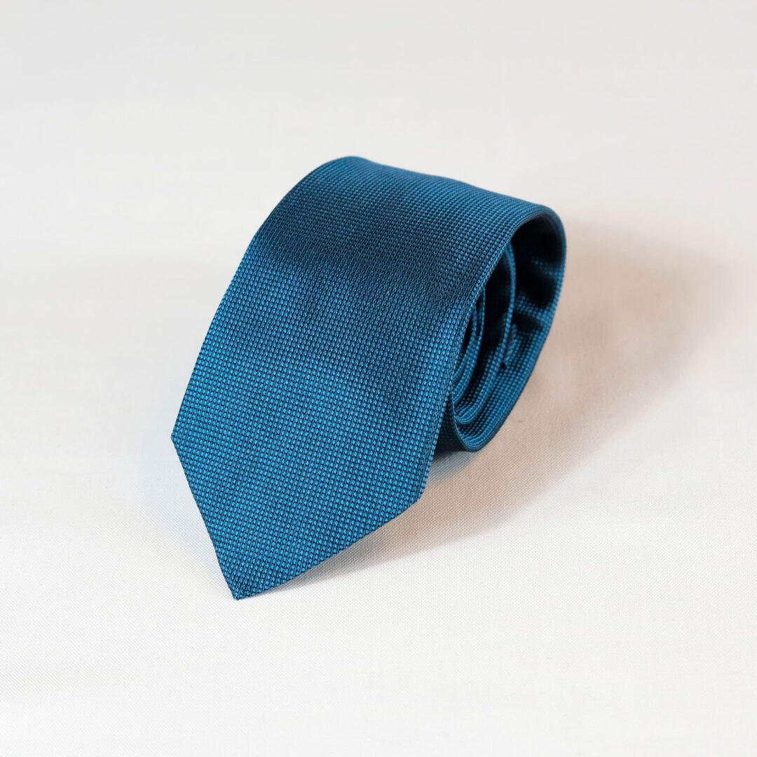 A blue tie is laying on the ground.