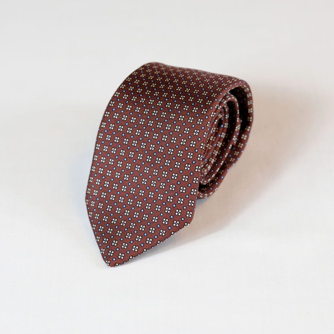 A brown tie with white and blue dots on it.