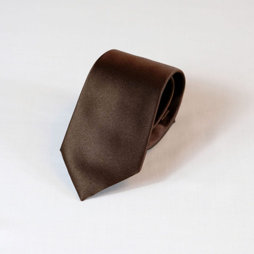 A brown tie is laying on the ground.