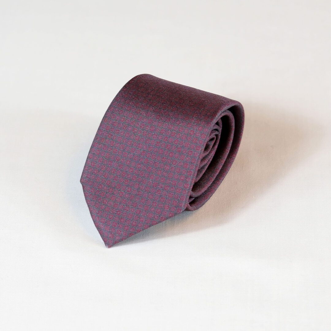 A purple tie is laying on the ground.