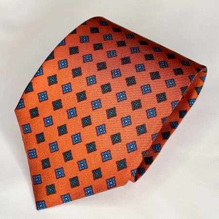 A close up of an orange tie with blue squares