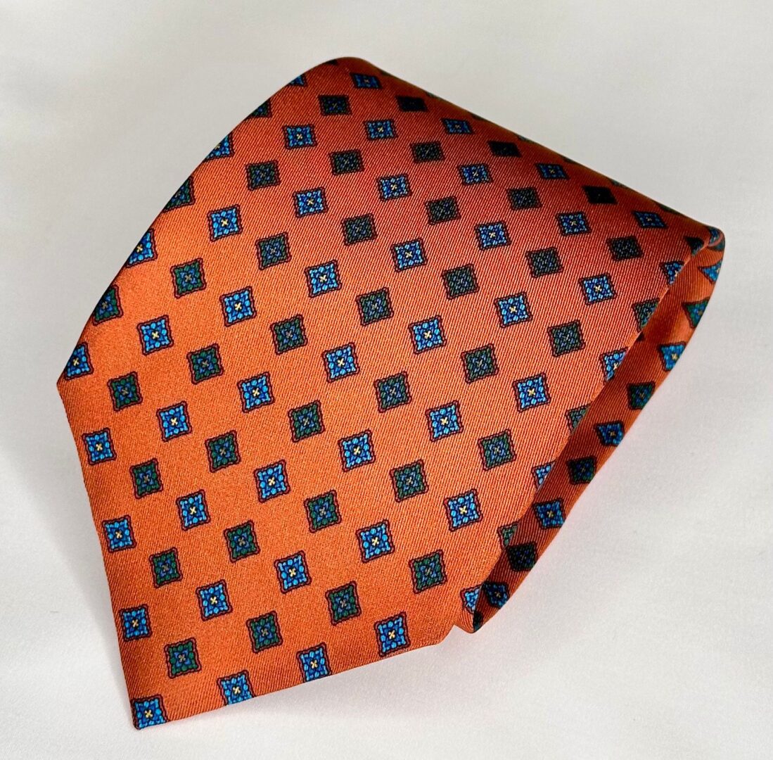 A close up of an orange tie with blue squares