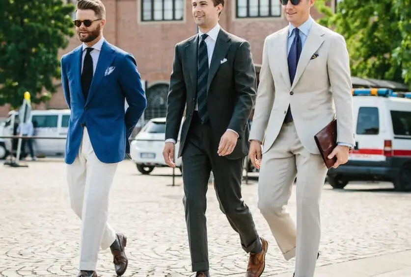 Three men in suits and ties walking down a street.