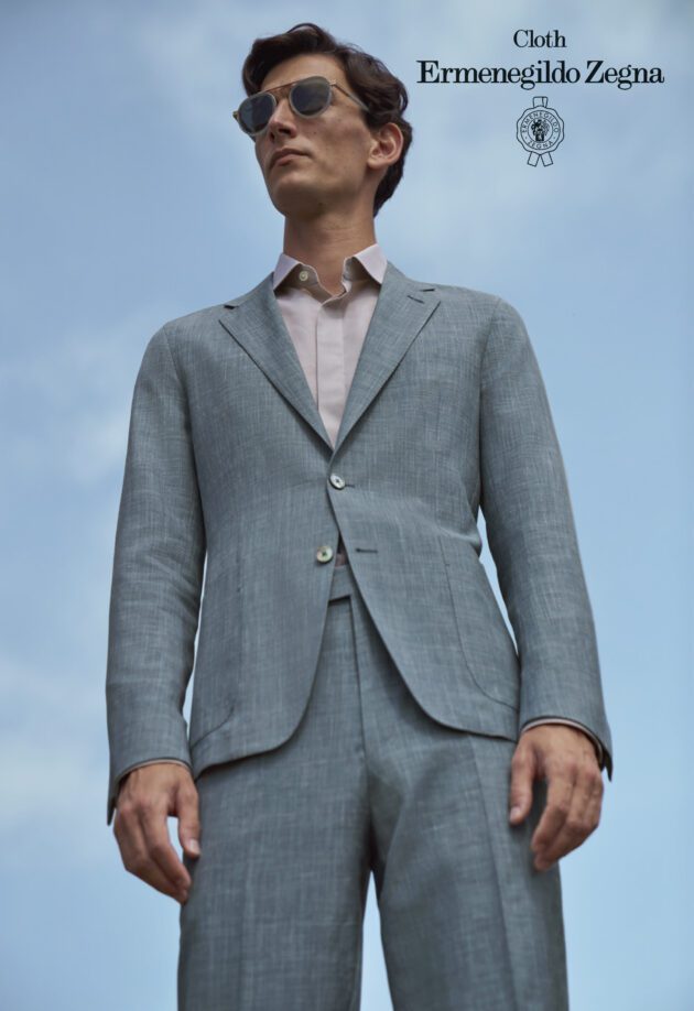 A man in a suit and tie standing on the beach.