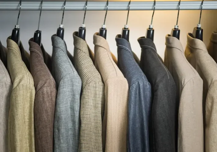 A row of suits hanging on clothes racks.